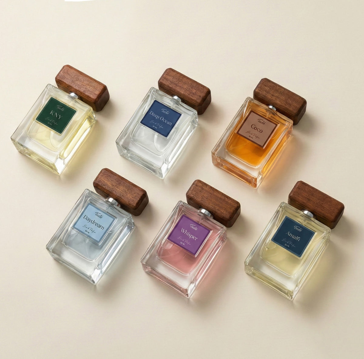 Set of eight small perfume bottles with wooden caps on a beige background